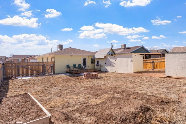 rear view of property with stucco siding, a fenced backyard, central AC unit, a residential view, and a garden