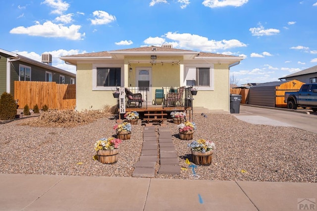 bungalow-style home featuring a porch, fence, and stucco siding