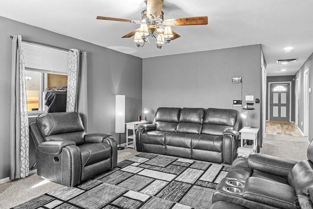 carpeted living room featuring baseboards, visible vents, and a ceiling fan