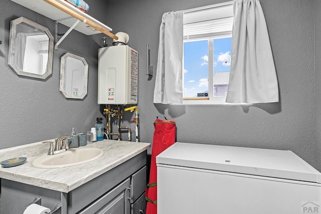 bathroom with tankless water heater, a textured wall, and vanity