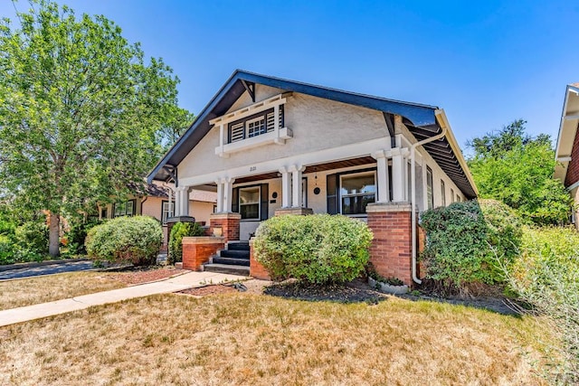 2121 N Greenwood St, Pueblo, CO 81003 - view of front facade with covered porch, brick siding, a front lawn, and stucco siding