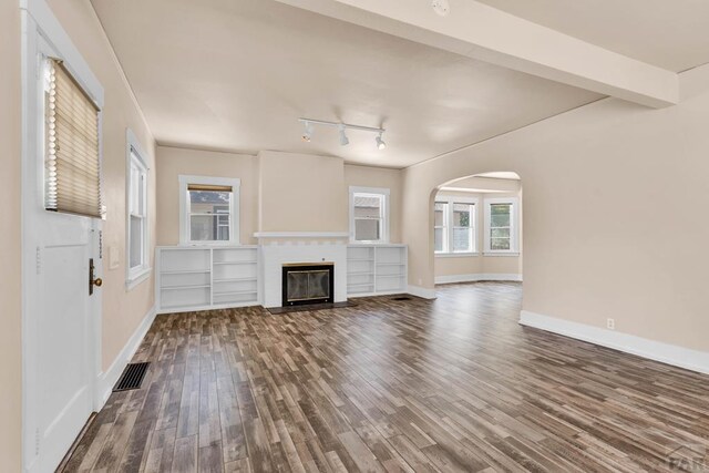 2121 N Greenwood St, Pueblo, CO 81003 - unfurnished living room with wood finished floors, track lighting, arched walkways, and a fireplace with flush hearth