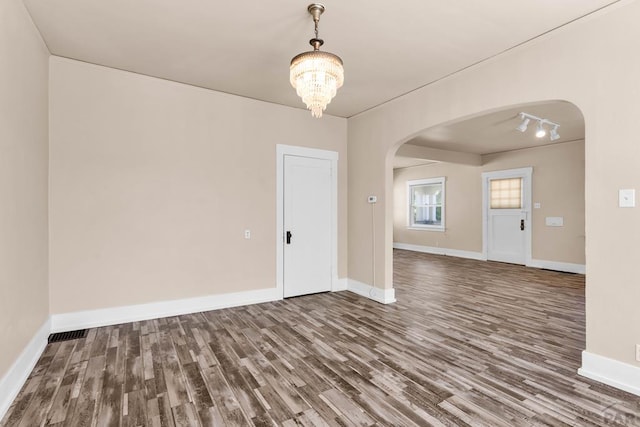 2121 N Greenwood St, Pueblo, CO 81003 - spare room featuring arched walkways, wood finished floors, a chandelier, and track lighting