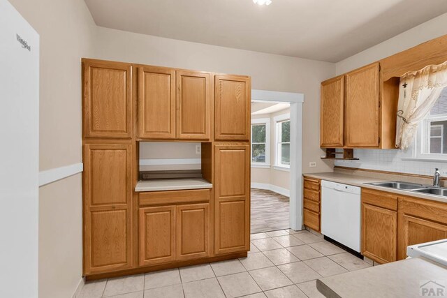 2121 N Greenwood St, Pueblo, CO 81003 - kitchen featuring dishwasher, light tile patterned floors, light countertops, backsplash, and brown cabinetry