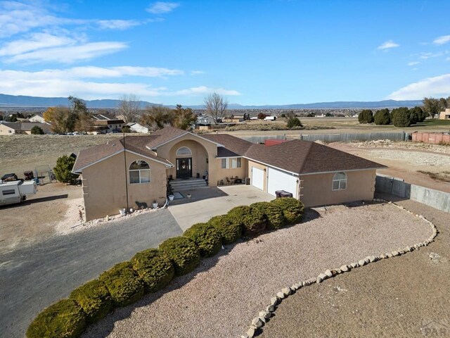 view of front facade with driveway, an attached garage, a mountain view, and stucco siding