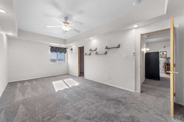 spare room with carpet, baseboards, a raised ceiling, and a ceiling fan