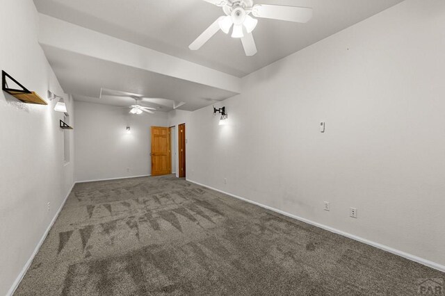 carpeted spare room featuring a ceiling fan and baseboards