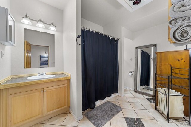 full bath featuring a shower with curtain, vanity, baseboards, and tile patterned floors