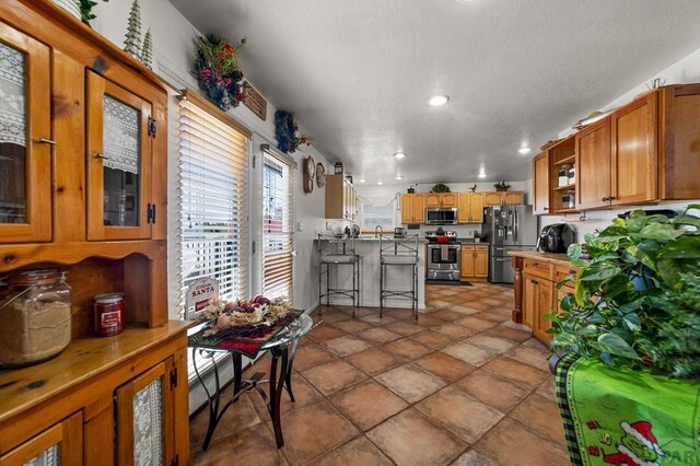 kitchen with recessed lighting, stainless steel appliances, light countertops, brown cabinets, and glass insert cabinets