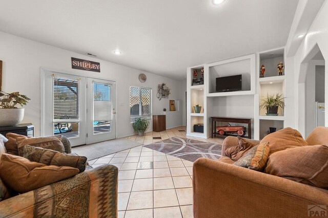 living room with light tile patterned floors, built in shelves, visible vents, and a fireplace