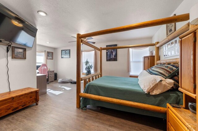 bedroom with ceiling fan, a textured ceiling, wood finished floors, and recessed lighting