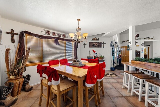 tiled dining space with a textured ceiling, baseboards, and a notable chandelier