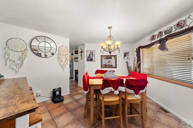 dining space featuring baseboards, a textured ceiling, visible vents, and a notable chandelier