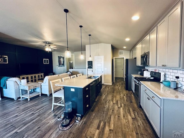 kitchen featuring dark wood-style flooring, stainless steel appliances, decorative light fixtures, and open floor plan