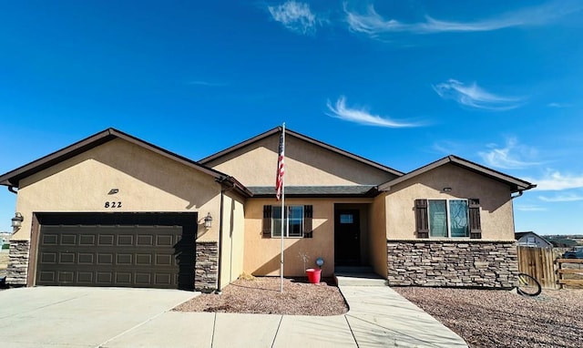 single story home featuring a garage, fence, stone siding, driveway, and stucco siding