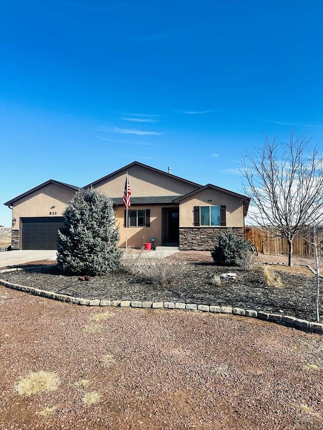 view of front of home featuring stone siding, fence, concrete driveway, and stucco siding