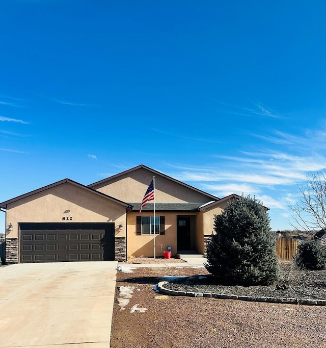 ranch-style home featuring stucco siding, fence, a garage, stone siding, and driveway