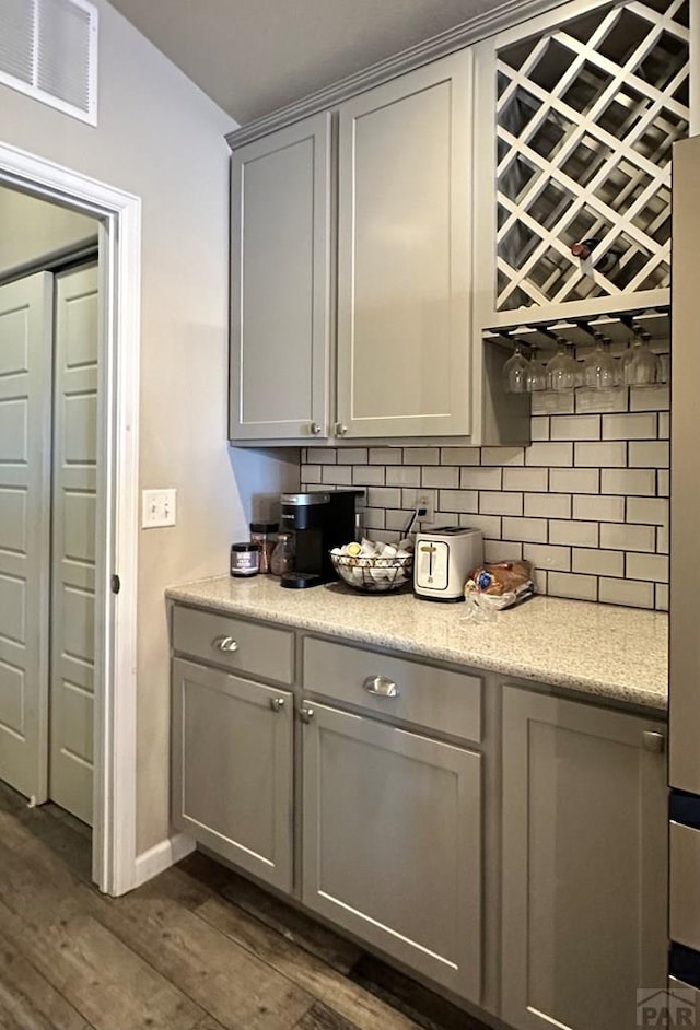 bar with baseboards, visible vents, dark wood finished floors, and backsplash