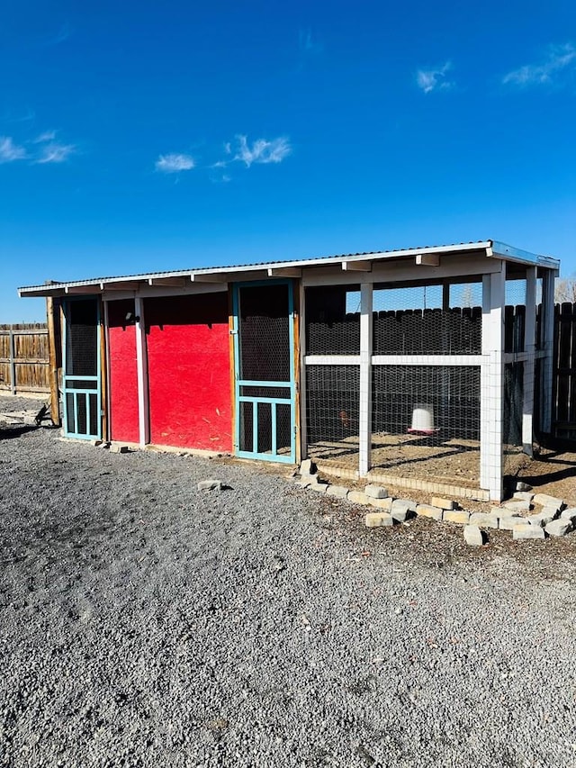 view of outdoor structure featuring fence and an outbuilding