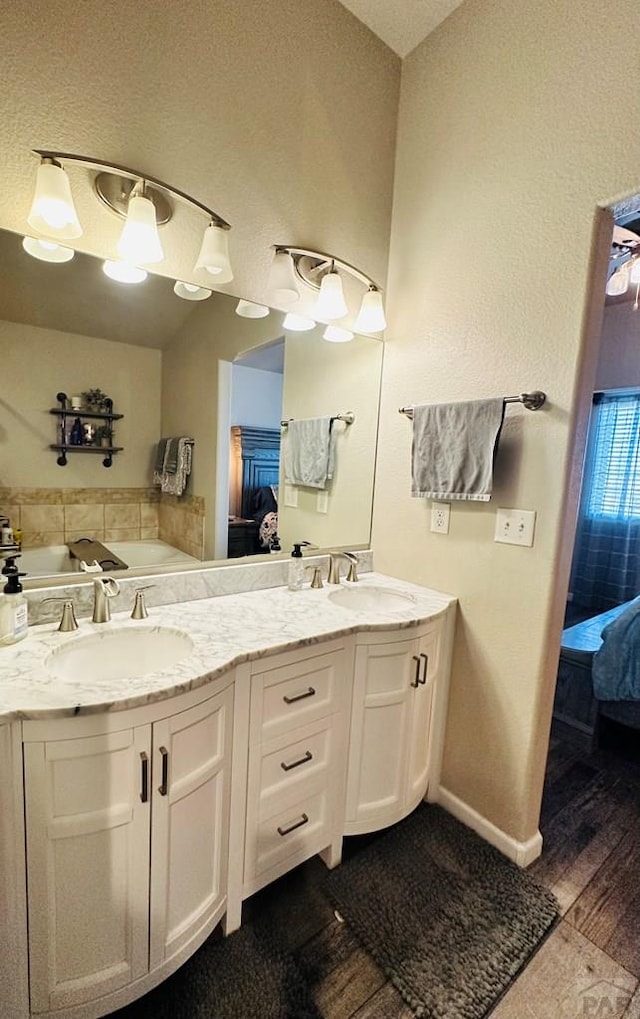 full bathroom with baseboards, connected bathroom, a sink, and double vanity