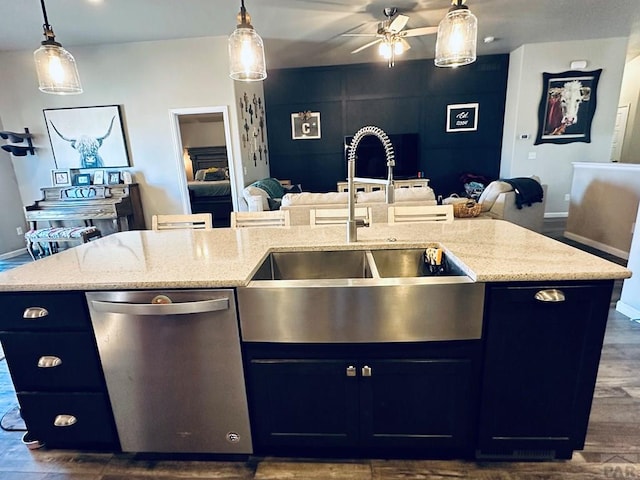 kitchen with pendant lighting, a sink, an island with sink, and stainless steel dishwasher