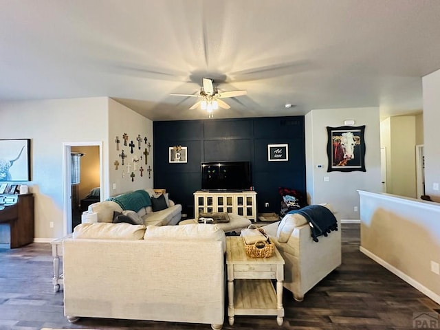 living area with dark wood-style floors, ceiling fan, and baseboards