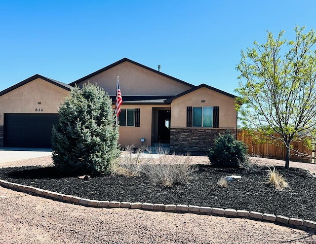 822 S Espanola Dr, Pueblo West, CO 81007 - view of front of house with fence, an attached garage, stone siding, stucco siding, and driveway