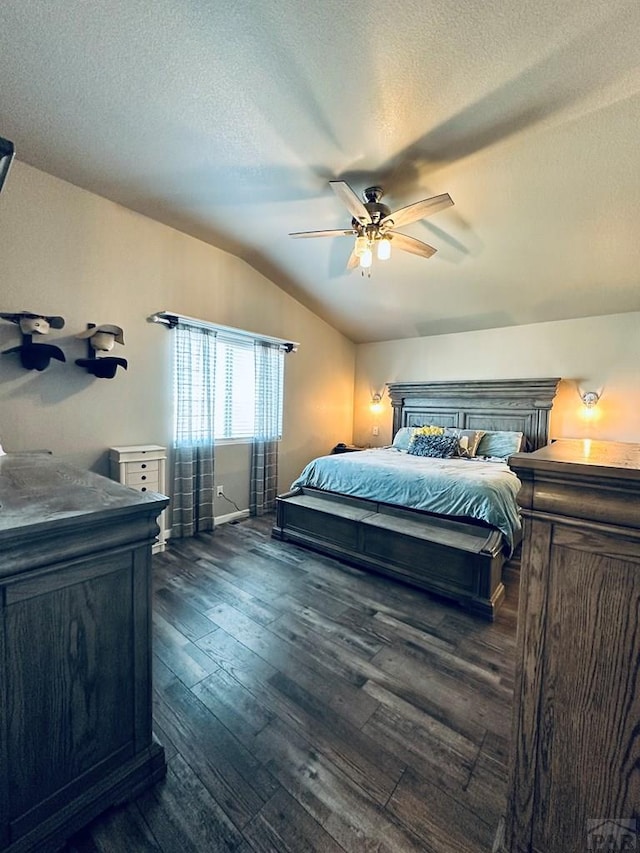 bedroom with dark wood-style floors, a textured ceiling, vaulted ceiling, and a ceiling fan