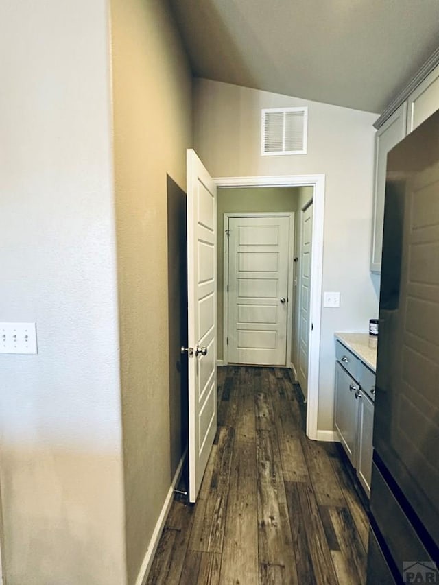 hall with lofted ceiling, dark wood-style flooring, visible vents, and baseboards