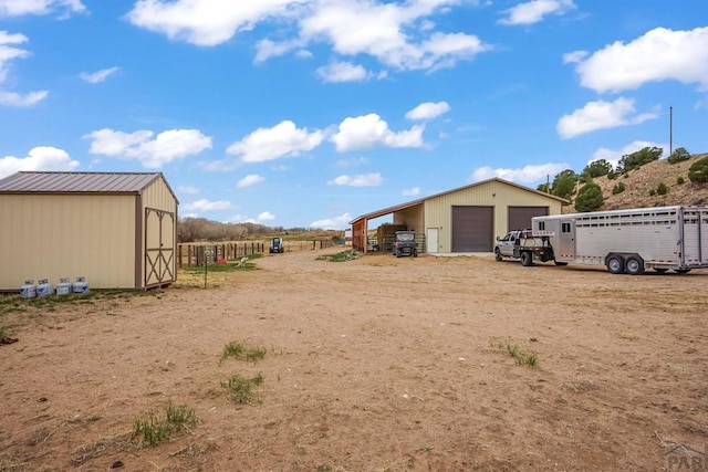 view of yard with fence, a detached garage, and an outdoor structure