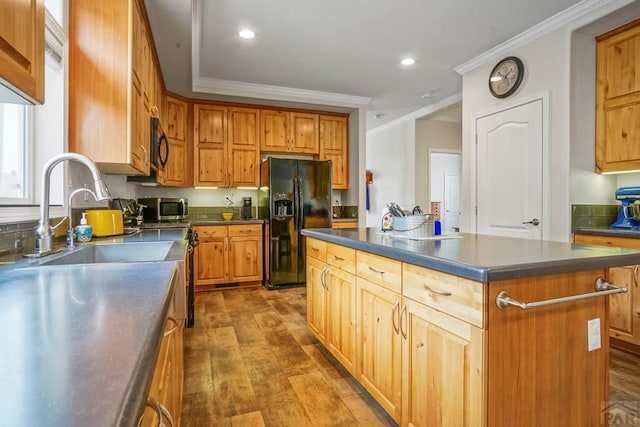 kitchen with a sink, black appliances, crown molding, a center island, and dark countertops