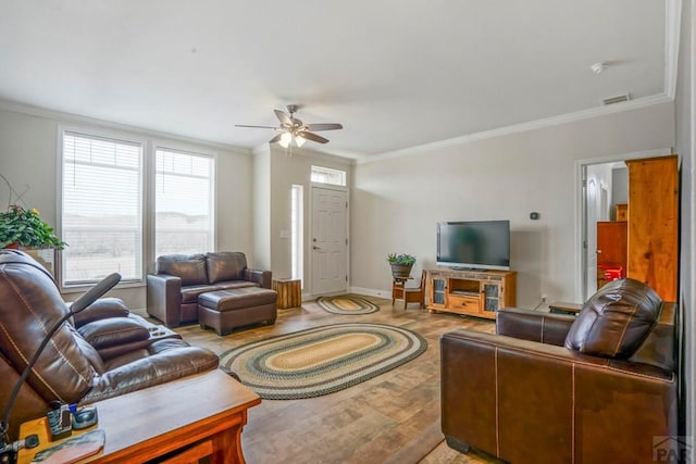 living area with baseboards, ceiling fan, crown molding, and wood finished floors