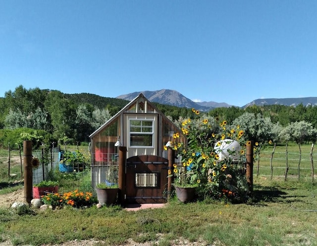 view of greenhouse featuring a mountain view and fence