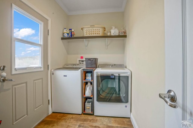 laundry area with ornamental molding, separate washer and dryer, light wood finished floors, and laundry area