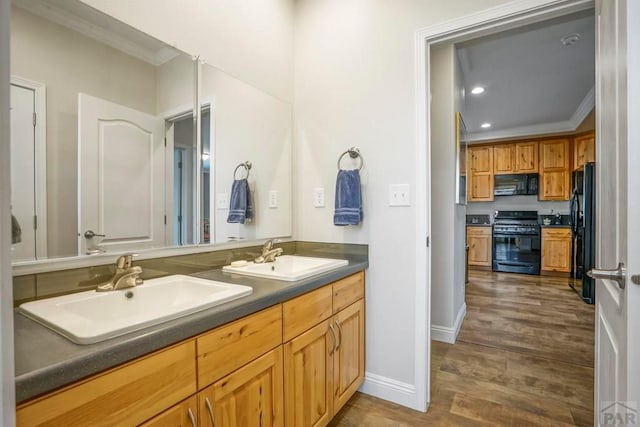 bathroom featuring ornamental molding, double vanity, a sink, and wood finished floors