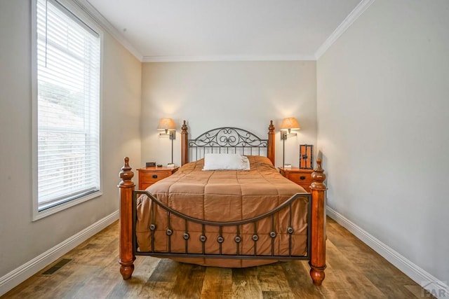 bedroom featuring crown molding, visible vents, wood finished floors, and baseboards