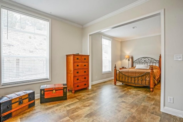 bedroom with baseboards, ornamental molding, and wood finished floors