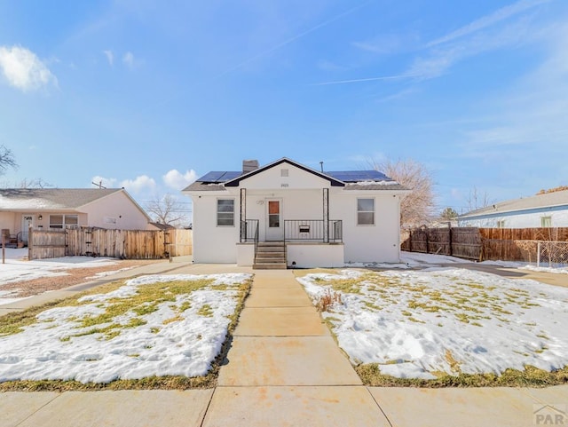 bungalow with fence private yard, solar panels, and stucco siding