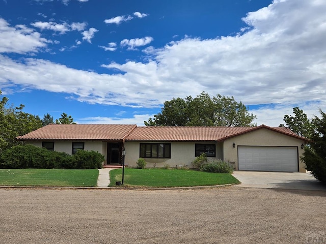 ranch-style house featuring a garage, concrete driveway, a tiled roof, a front lawn, and stucco siding