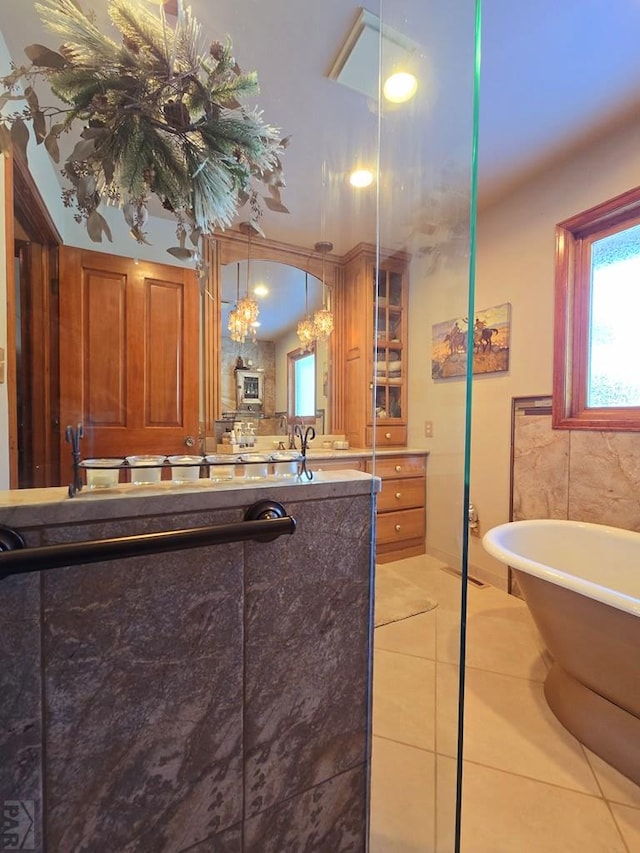 bathroom with a freestanding tub, tile patterned flooring, and vanity