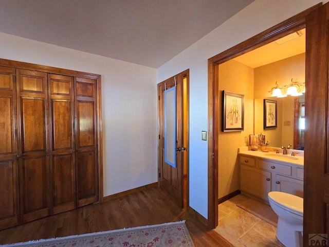 bathroom featuring toilet, wood finished floors, vanity, and baseboards