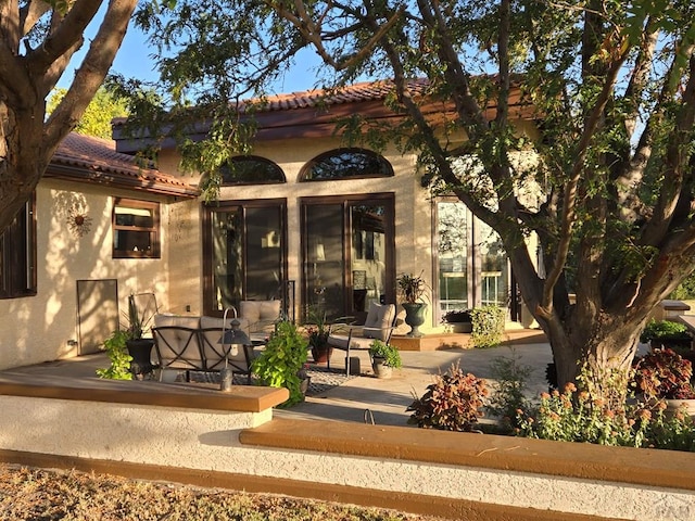 back of property featuring a patio, a tiled roof, and stucco siding