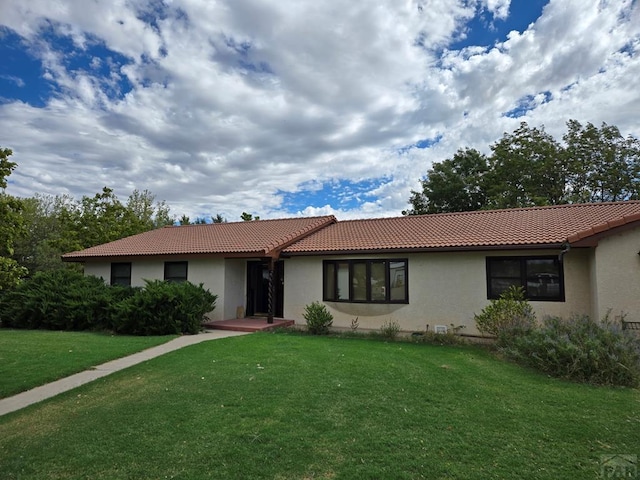 single story home with a tiled roof, a front lawn, and stucco siding