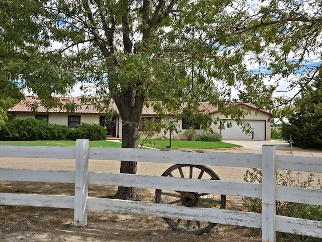 exterior space featuring an attached garage, a fenced front yard, a tile roof, and concrete driveway