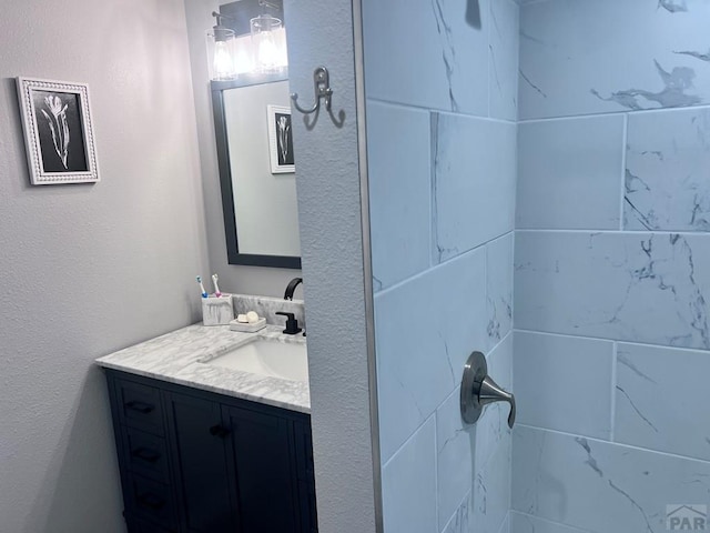 bathroom with a tile shower and vanity