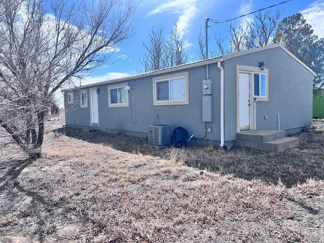 rear view of house featuring central air condition unit and stucco siding