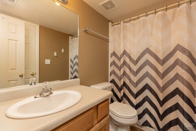 full bath with toilet, vanity, and visible vents