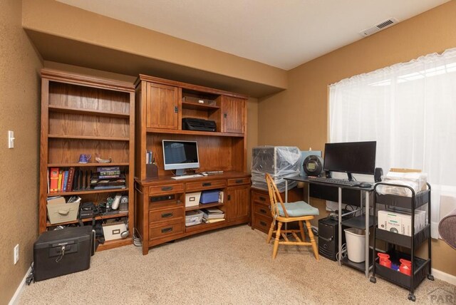 office space featuring baseboards, visible vents, and light colored carpet