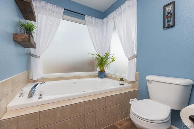 bathroom with a garden tub and toilet