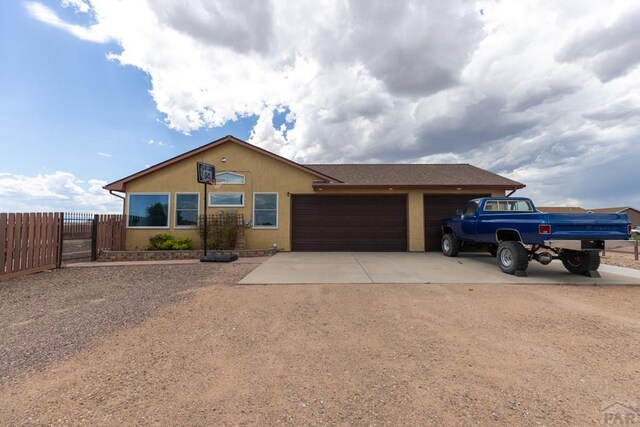 single story home featuring an attached garage, fence, concrete driveway, and stucco siding